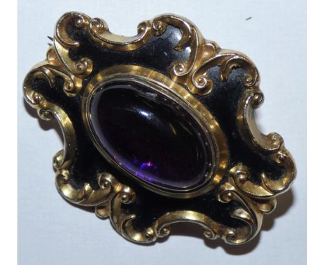 A Victorian gold, black enamel brooch set with a cabochon amethyst