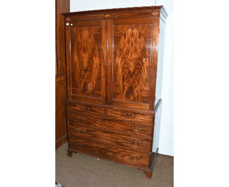 A George III inlaid mahogany linen press, with three patera to the cornice, oval figured mahogany panels to the doors, raised