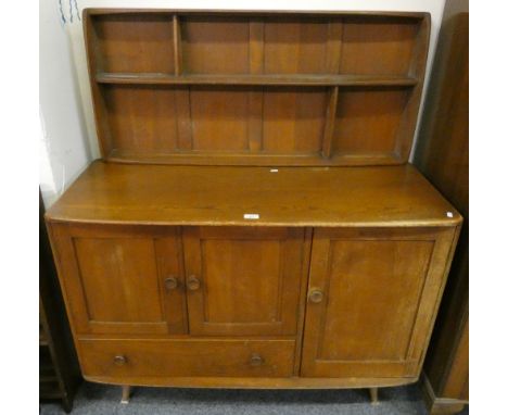 An Ercol Windsor beech and elm sideboard, with a two door cupboard above a deep drawer flanked by a shelved cupboard with cut