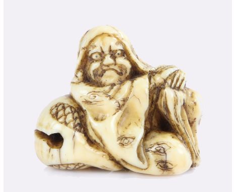 Japanese Edo period marine ivory netsuke, Daikoku shown with an irreverent expression, rests on a temple gong Mokugyo, signed