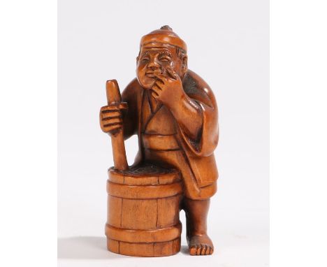 Japanese wood netsuke, carved as a man standing above a container, signed to the base, 5cm high