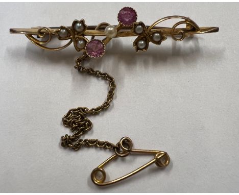A 15 carat gold bar brooch set with seed pearl and rubies with safety chain. 2.6gm. 