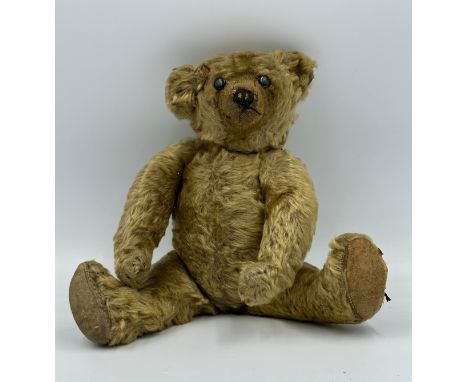 An early 20thC straw filled Teddy with button eyes and long snout and paws. Approx. 33cm long. 