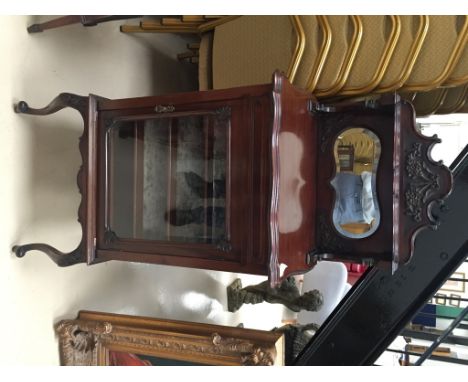 An Edwardian mahogany display case/music cabinet: the top section with shelf and mirror and the glazed door opening to reveal