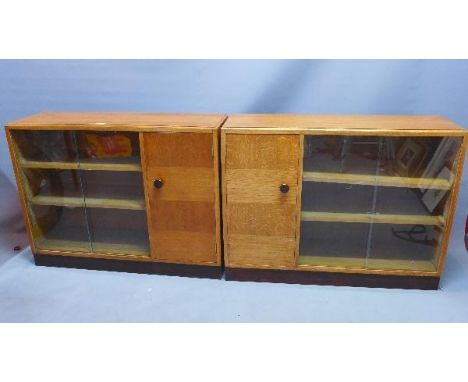 A pair of mid 20th century light oak bookcases, with two glass sliding doors, beside cupboard door, raised on plinth base, H.