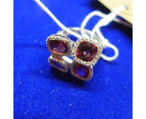 A ladies 18ct white gold, ruby and diamond ring, having four cushion cut rubies within diamond set mounts, the shoulders inse