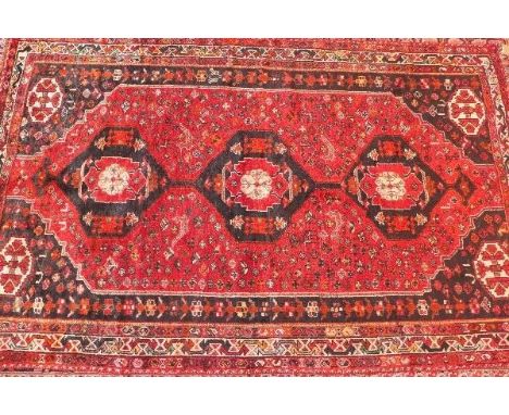 A fine North West Persian Afshar carpet, having triple pole medallion with repeating petal motifs on a terracotta field withi