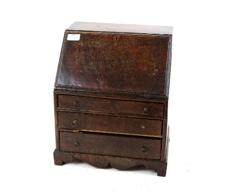 Miniature oak George III style bureau, the sloping fall enclosing an empty interior over three graduated drawers on a shaped 