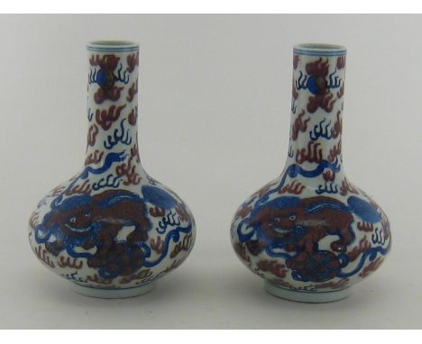 A pair of Chinese ceramic vases, each with globe base and tall neck, painted in blue and manganese with lions amid clouds. Tw