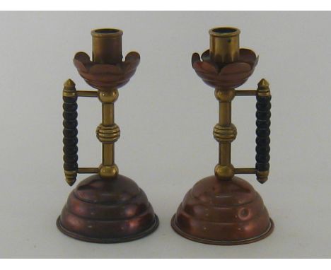 A pair of Arts and Crafts brass and copper candlesticks with bobbin turned ebony handles after W.A.S. Benson, unmarked. Ht. 1