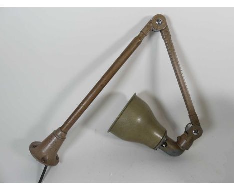 An early 20th century worktop mounted lamp having a hinged adjustable arm, maximum height 76cm