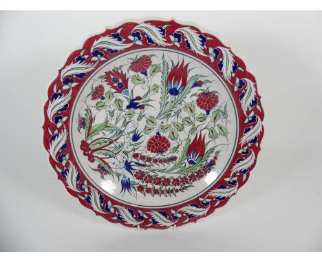 An Turkish Iznik style polychrome earthenware charger having shaped rim and foliate decoration, dia. 40cm