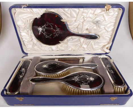 A George V ladies silver backed and tortoiseshell dressing table set, to include hand mirror, hair brushes, hand brushes and 