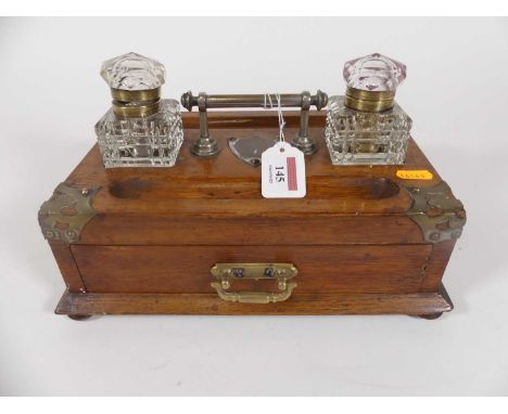 A Victorian light oak desk stand, having gothic style brass mounts, and twin cut glass inkwells with pen trays and drawer bel