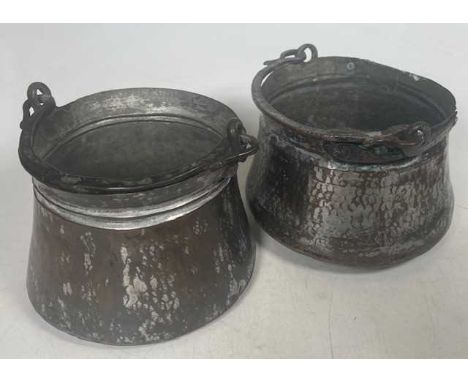 An Eastern, possibly Islamic, hammer beaten metal cauldron having an iron handle, dia. 19cm, together with another similar