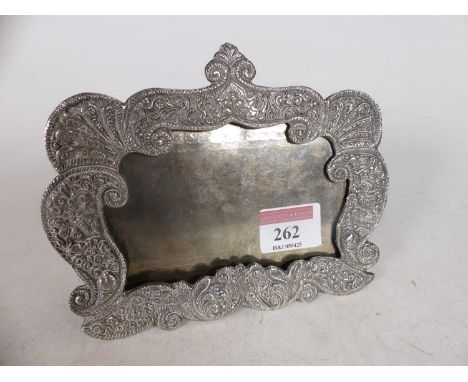 An early 20th century Eastern white metal photo frame of shaped rectangular form with embossed scrolling decoration, further 