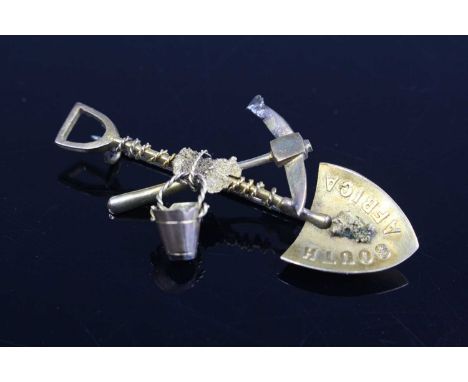 A 15ct gold brooch fashioned as a South African goldminer's shovel, axe and bucket, with steel pin, 5cm, in original fitted c