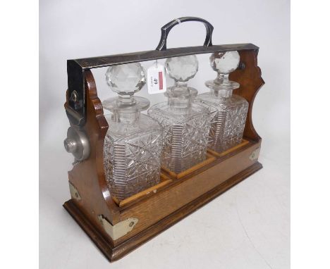 An Edwardian silver plated mounted oak three-decanter tantalus, locked and lacking key, h.29cm