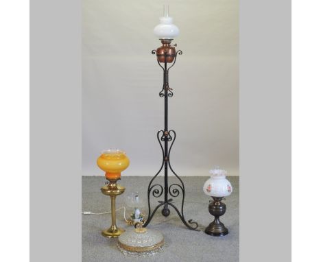 A wrought iron standard oil lamp, together with a collection of oil lamps and shades
