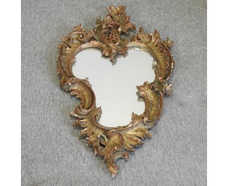 A ornate gilt framed wall mirror, 120 x 64cm overall, together with a brass fender, and a brass top occasional table (3)