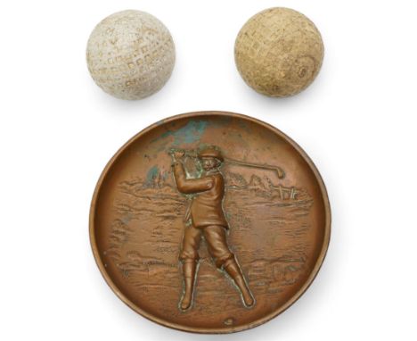 Two moulded mesh pattern gutta-percha golf balls each marked 'Made in England' and a copper circular shallow dish with a rais