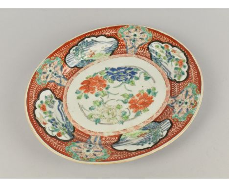 A Japanese Porcelain Oval Platter Decorated with Exterior Cartouches on Red Patterned Ground with Central Floral Motif, Signe