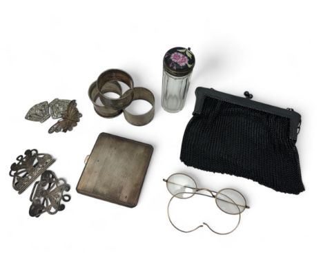 A silver cigarette case, 3 silver napkin rings, a glass bottle with a painted lid, gold plated spectacles, etc