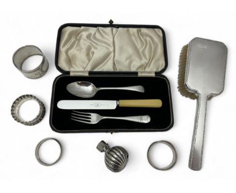 A collection of silver and white metal items. Includes a cutlery set with silver knife and fork, two silver napkin holders, a