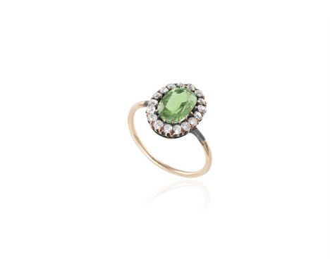 A LATE VICTORIAN DEMANTOID GARNET AND DIAMOND CLUSTER RING, CIRCA 1880, RUSSIANThe central oval-shaped demantoid garnet weigh