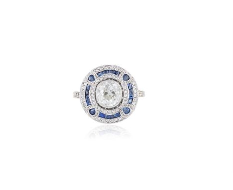 A DIAMOND AND SAPPHIRE RINGThe collet-set cushion-shaped diamond, within a rose-cut diamond and calibré-cut sapphire surround