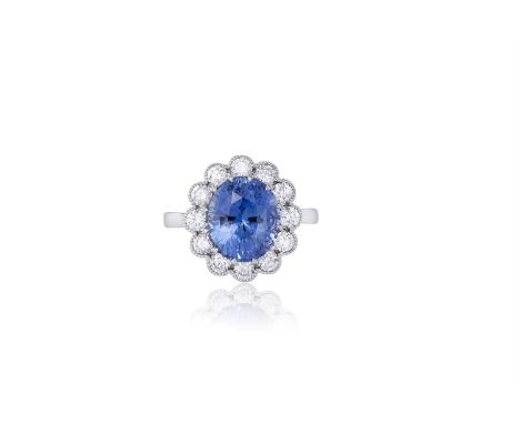 A SAPPHIRE AND DIAMOND CLUSTER RINGThe oval-shaped sapphire, weighing 5.16cts, within a surround of millegrain-set round bril