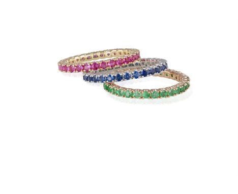 A SET OF THREE FULL HOOP ETERNITY RINGSEach set with circular-cut emeralds, rubies and sapphires, within four-claw setting, m