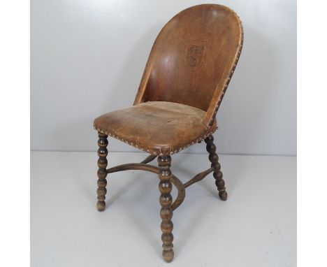 An antique mahogany and leather upholstered side chair, with tooled armorial lion decoration, raised on bobbin turned legs wi