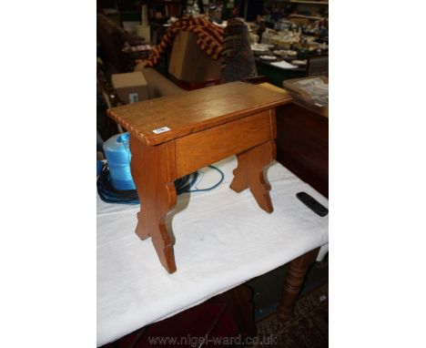 A reproduction light Oak Priory style plank Stool with moulded edge rectangular top on two fret cut plank legs with carved fr