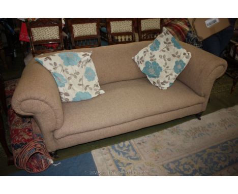 A Victorian three seater Chesterfield Sofa with roll arms and on turned legs with castors, upholstered in oatmeal coloured fa