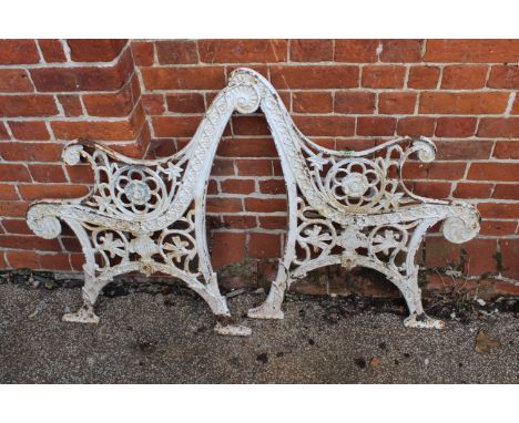 A pair of cast iron garden bench ends with pierced foliate decoration and scrolling arms