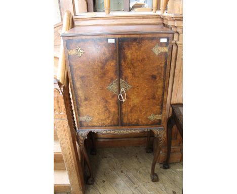 A vintage Queen Anne style walnut cocktail cabinet with fitted mirror interior on cabriole legs and ball and claw feet 