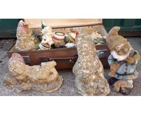 A vintage suitcase containing various garden ornaments including gnomes