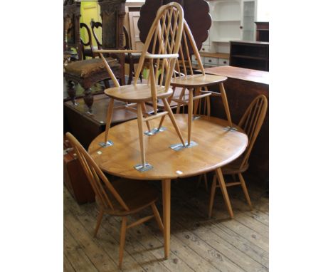 A mid Century light Ercol dining table with four stick back dining chairs and an additional carver