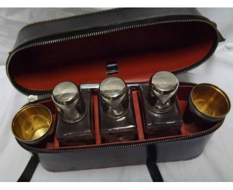 Early 20th Century travelling Drinks Set in black leather zipped case comprising three clear glass spirit bottles, with white