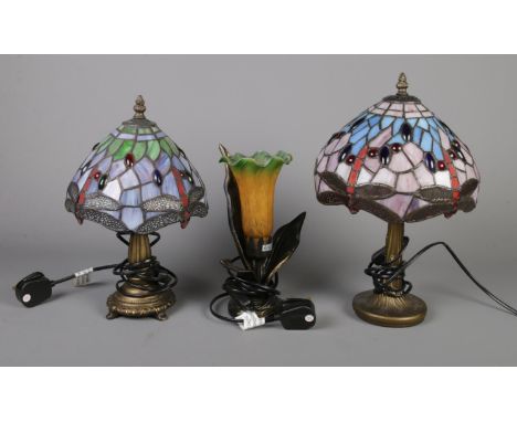 Three decorative desk lamps. To include two small Tiffany style lamps with dragon fly design and a floral example. H: 25cm.  