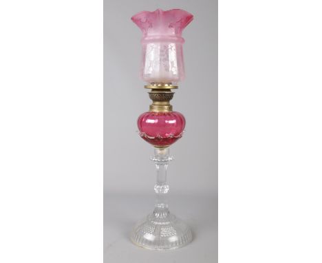 A Victorian cranberry glass oil lamp. (48cm height)  Chip to bottom of shade.