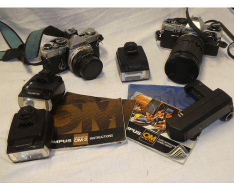 An Olympus OM10 camera with 28-80mm lens and an Olympus OM2 camera together with flash units and instruction books