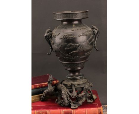 A Japanese dark patinated bronze ikebana vase, cast with cranes amongst clouds and mythical beasts, the base with a ferocious