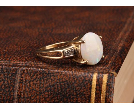 A 9ct yellow gold white opal and diamond dress ring, the oval cabochon white opal measures approx. 11mm x 8.94mm, the opal sh