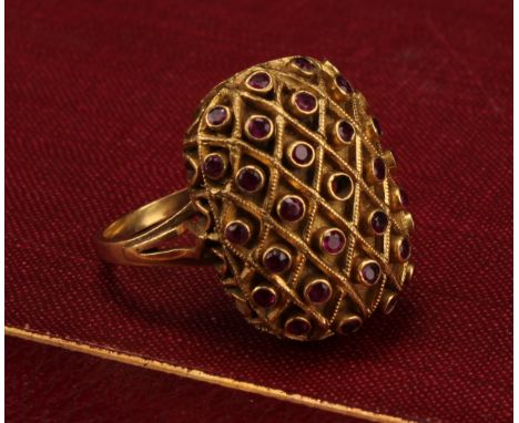 A domed rectangular shaped ruby ring, crisscrossed cresting set with twenty nine deep pink round brilliant cut rubies, (two o