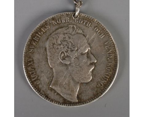 A Swedish 1868 silver coin on chain. 'Carl XV Sveriges Norr. Goth. Och Vend. Konung' to one side and 'Hand Skall Med Lang Byg