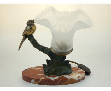 A 1950's bronzed parcel gilt spelter table lamp, cast with a bird on a branch beside an opaque glass shade on oval marble bas