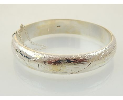 A silver bangle, engraved with stylised flowers. internal diam. 6cm