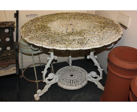 A white cast iron garden table with circular pierced top and under-shelf, on scroll legs, 93cm